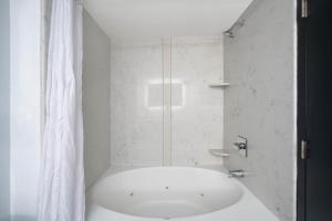 baño blanco con ducha y lavamanos en La Quinta by Wyndham Raleigh Downtown North, en Raleigh