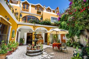 un edificio amarillo con una mesa y una sombrilla en La Hostería Boutique Hotel en Arequipa