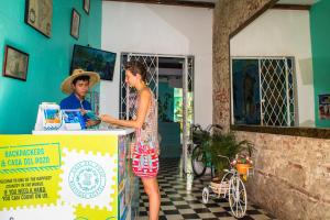 a woman standing at a counter with a man behind it at Casa Del Pozo Boutique Hostel in Cartagena de Indias