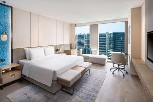 a bedroom with a large white bed and a living room at Radisson Blu Hangzhou Xintiandi in Hangzhou