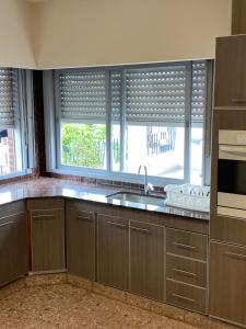 a kitchen with a sink and two windows at Departamento Ezeiza Centro in Ezeiza