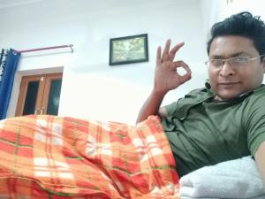 a man sitting on a couch with his hand in the air at vinyaka p.g.house in Rāmnagar