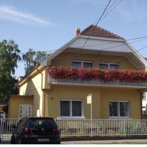 ein gelbes Haus mit einem Balkon mit roten Blumen in der Unterkunft Matild Apartmanház in Siófok