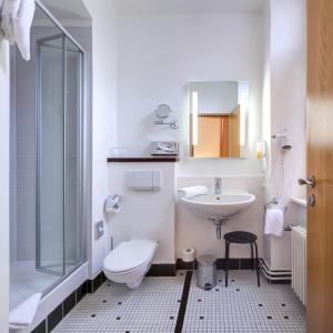 a white bathroom with a toilet and a sink at Best Western Hotel Kurfürst Wilhelm I. in Kassel