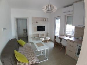 a living room with a couch and a desk and a kitchen at Apartman Dajoda 1 in Bijela