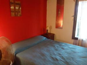 1 dormitorio con 1 cama con pared roja en Metamorfosis, en Aguas Dulces