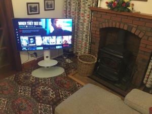 sala de estar con chimenea y TV en Brackfield House Deal 49, en Killaloo
