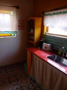 a kitchen with a sink and a red counter top at Los Remenizos Cabañas de Montaña in Belén