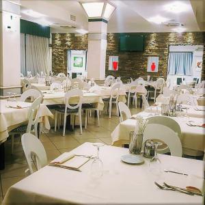 uma sala de jantar com mesas brancas e cadeiras brancas em Hotel Lenotel em Leno