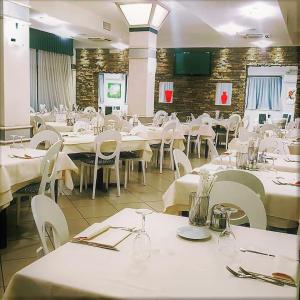 une salle à manger avec des tables et des chaises blanches dans l'établissement Hotel Lenotel, à Leno