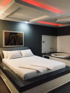 1 dormitorio con 1 cama blanca grande y bañera en Motel Anonimus, en Passo Fundo