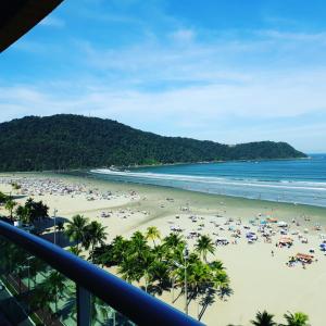 a beach with a crowd of people and the ocean at Apto Varanda Gourmet frente ao mar com Wi-Fi in Praia Grande