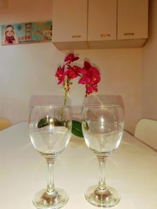 due bicchieri da vino su un tavolo con un vaso con fiori rossi di Oliver Suite Plaza Mayor a Madrid