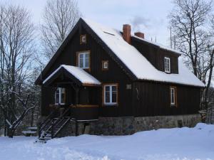 una casa negra con nieve en el techo en Chata na końcu świata en Żytkiejmy