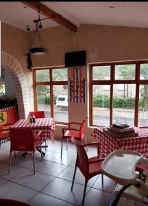 una sala da pranzo con sedie rosse, tavoli e finestre di Turtle Creek - Leatherback a Umkomaas