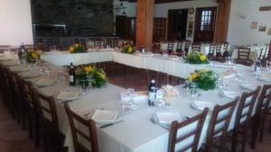 un lungo tavolo con tavoli e sedie bianchi e fiori di Il Falco E La Volpe a Settimo Vittone