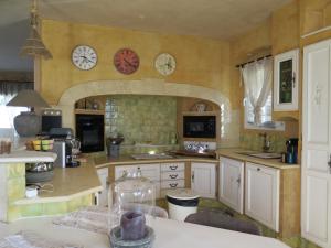 a large kitchen with white cabinets and clocks on the wall at Villa fiora classée 4 étoiles in Martigues
