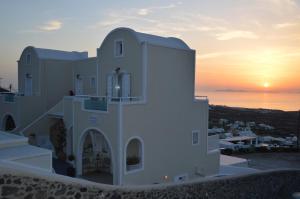 a building with the sunset in the background at Kiklamino Sunset Studios in Oia