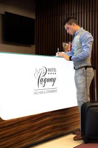 Um homem em pé num palco a escrever num cartaz em Hotel Pagony Wellness em Nyíregyháza
