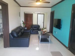 sala de estar con muebles de cuero negro y TV en Inn The Town en Port Antonio