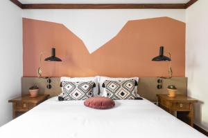 a bedroom with a large white bed with pillows at Selina Gerês in Geres