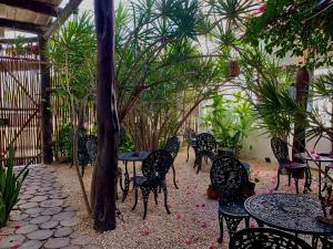 a patio with tables and chairs in a garden at Lo Nuestro Petit Hotel Tulum in Tulum