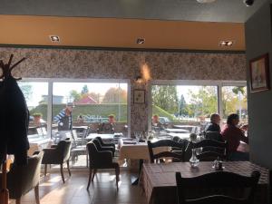 un restaurante con gente sentada en las mesas de una habitación en Aurora Panzió, en Bük