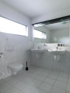 a white bathroom with two sinks and a toilet at B & B Waalre in Waalre