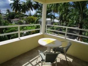 a table and two chairs on a balcony with palm trees at Vida Mejor - East Pool in Saint James