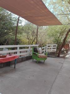 a green bench under an umbrella next to a fence at Hospedaje Rural Casa de Felix in San Pedro de Atacama