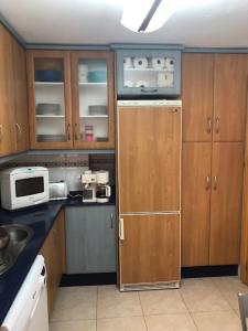 a kitchen with wooden cabinets and a refrigerator at Apartamento las Yucas - Aguilas in Águilas