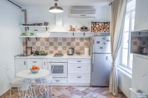 a white kitchen with a table and a refrigerator at Serene apartment ELENA in Zagreb