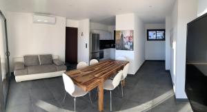 a kitchen and living room with a wooden table and chairs at Résidence Les Jardins du Fort in Porticcio