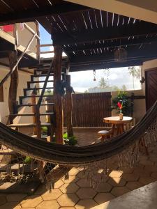a hammock on a patio with a table and stairs at Pousada Rio Sagi in Baía Formosa