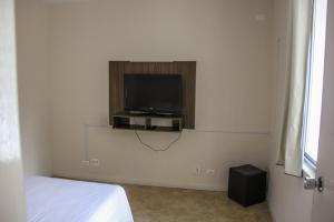 a bedroom with a tv on a white wall at Juveve Loft Apartment in Curitiba