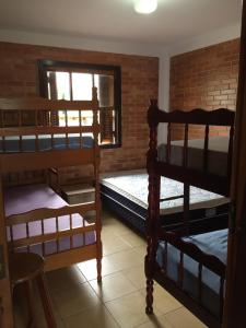 Zimmer mit 3 Etagenbetten und Ziegelwand in der Unterkunft Pousada Residencial Paineiras in Guaratuba