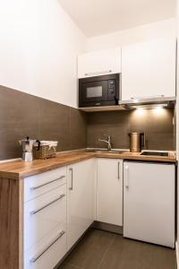 a kitchen with white cabinets and a microwave at Apartmán Dagmar in Bešeňová