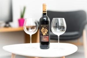 a bottle of wine sitting on a table with two wine glasses at Apartmani Sterija in Novi Sad