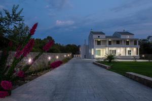 a driveway leading to a large white house with lights at Villa Athos in Gouvia