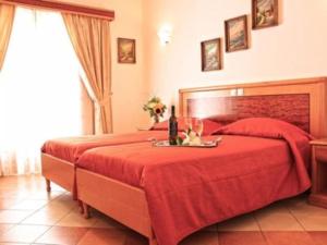 a bedroom with a red bed with a table on it at Hotel Anatolia in Ano Mera