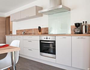 a white kitchen with white cabinets and a stove at Les coeurs de Cachemire in Breuschwickersheim