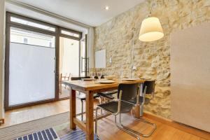 een eetkamer met een houten tafel en een stenen muur bij Designer Haus in Armissan