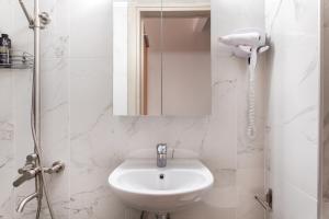Un baño blanco con lavabo y espejo. en Cityscape, en Tesalónica