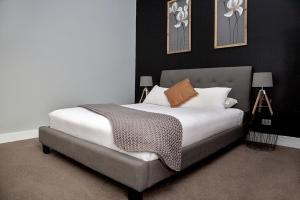 een slaapkamer met een bed met witte lakens en bruine kussens bij Revive Central Apartments in Temora