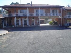 a large brick building with a parking lot in front of it at Coachmans Rest Motor Lodge in Coonabarabran