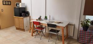 a kitchen with a desk with three chairs and a refrigerator at Lala's Home in Ushuaia