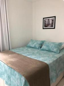 - une chambre dotée d'un lit avec des draps bleus et une photo sur le mur dans l'établissement Apartamento 3 quartos , Bairro Amazonas, à Contagem