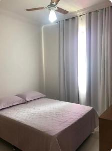 a bedroom with a bed with a ceiling fan and a window at Apartamento 3 quartos , Bairro Amazonas in Contagem