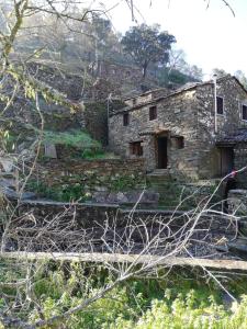 una vieja casa de piedra al lado de una colina en Casa de Baixo, en Lousã