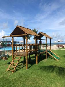 a wooden playground with a swing set next to the beach at Muro Alto Suites - Marupiara in Porto De Galinhas